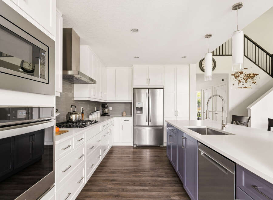 Experience modern luxury in this stunning kitchen, featuring sleek white cabinetry, a spacious island with a built-in sink, and high-end stainless steel appliances.