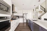 Experience modern luxury in this stunning kitchen, featuring sleek white cabinetry, a spacious island with a built-in sink, and high-end stainless steel appliances.