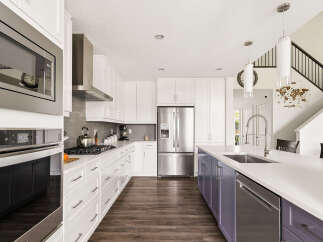 Experience modern luxury in this stunning kitchen, featuring sleek white cabinetry, a spacious island with a built-in sink, and high-end stainless steel appliances.
