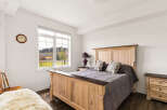 This charming bedroom features a spacious wooden bed with a decorative headboard, complemented by a matching nightstand and dresser.