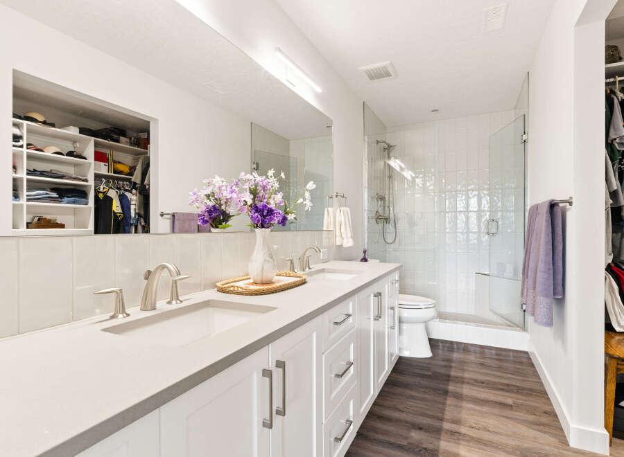 This modern bathroom features a spacious double vanity with sleek silver fixtures and ample counter space.