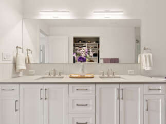 This modern bathroom features a spacious double vanity with two sinks, sleek brushed nickel faucets, and ample storage beneath.