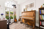 Experience the joy of music in this beautifully appointed room, featuring a classic upright piano and a collection of guitars.
