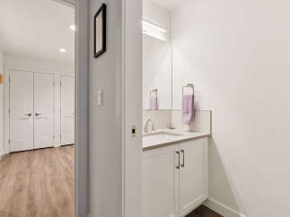 Step into a bright and modern hallway featuring a sleek vanity with a silver faucet and a plush purple towel.