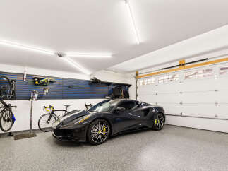 This spacious garage features a sleek dark sports car and two bicycles, perfect for the automotive enthusiast or cycling aficionado.