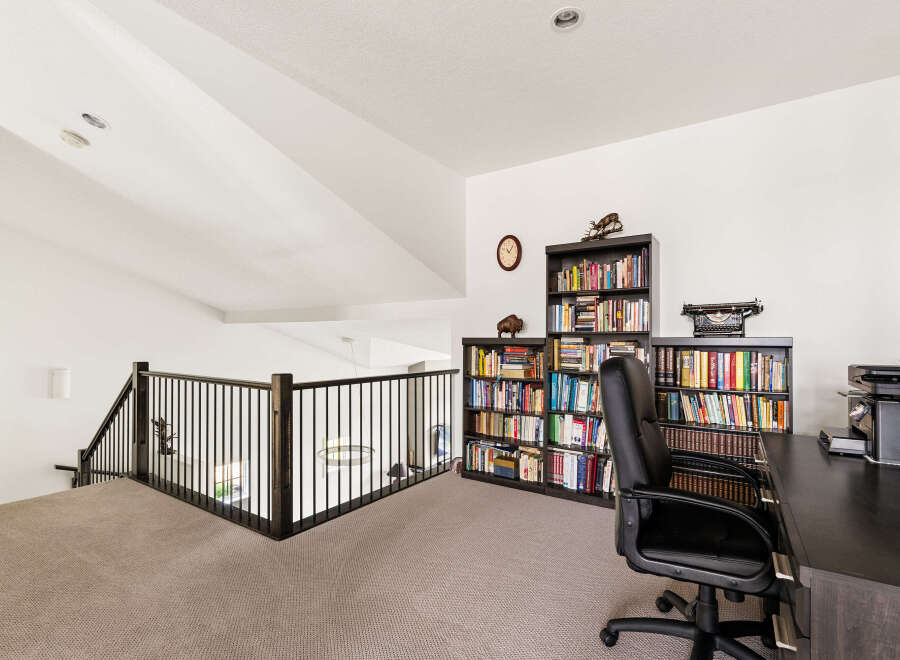 Discover a dedicated home office space with ample storage, featuring floor-to-ceiling bookshelves filled with a diverse collection.