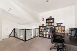 Discover a dedicated home office space with ample storage, featuring floor-to-ceiling bookshelves filled with a diverse collection.