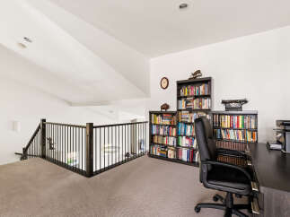 Discover a dedicated home office space with ample storage, featuring floor-to-ceiling bookshelves filled with a diverse collection.