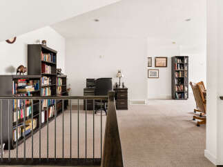 This spacious loft area features a dedicated home office with ample built-in bookshelves and a comfortable desk setup.