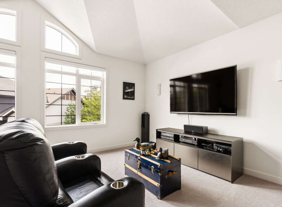 Experience ultimate relaxation in this home theater room, featuring plush black leather recliners with built-in cup holders.