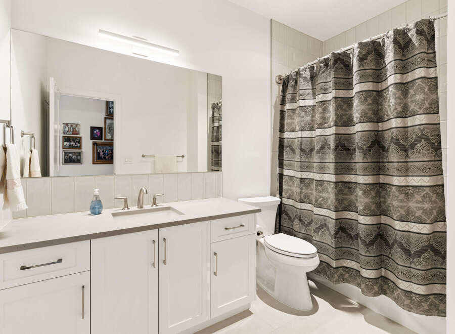 This modern bathroom features a sleek vanity with ample storage and a clean white countertop.