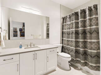 This modern bathroom features a sleek vanity with ample storage and a clean white countertop.