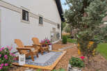 Enjoy outdoor living with this charming patio featuring two Adirondack chairs and a decorative rug, perfect for relaxing evenings.