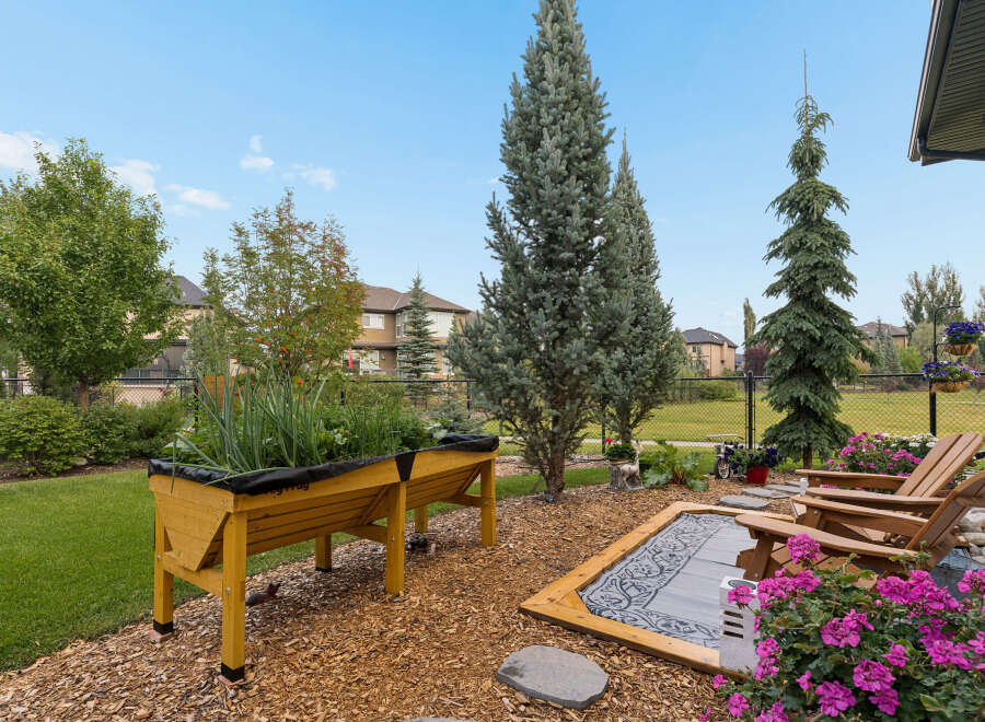 Enjoy outdoor living in this beautifully landscaped backyard, featuring a raised garden bed perfect for growing your own vegetables.