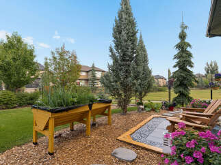 Enjoy outdoor living in this beautifully landscaped backyard, featuring a raised garden bed perfect for growing your own vegetables.
