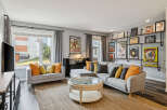 Step into this inviting living room, featuring a spacious sectional sofa adorned with vibrant accent pillows, perfect for cozy gatherings.