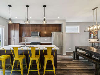 Experience modern living in this stunning kitchen featuring rich espresso cabinetry and a sleek white quartz island, perfect for casual dining or entertaining.