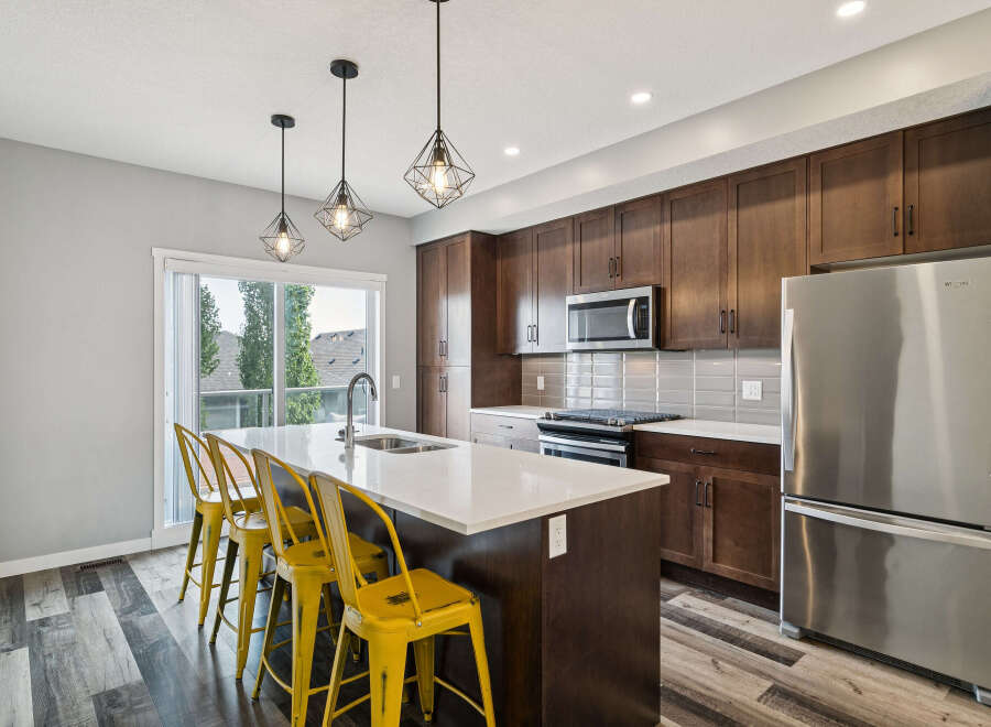 Experience modern living in this stunning kitchen featuring dark wood cabinetry, a sleek quartz island with seating, and stainless steel appliances.