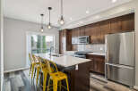 Experience modern living in this stunning kitchen featuring dark wood cabinetry, a sleek quartz island with seating, and stainless steel appliances.