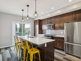 Experience modern living in this stunning kitchen featuring dark wood cabinetry, a sleek quartz island with seating, and stainless steel appliances.