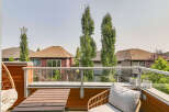 Enjoy outdoor living on this modern balcony, featuring a comfortable seating area with a hanging chair and a stylish wicker chair with cushions.