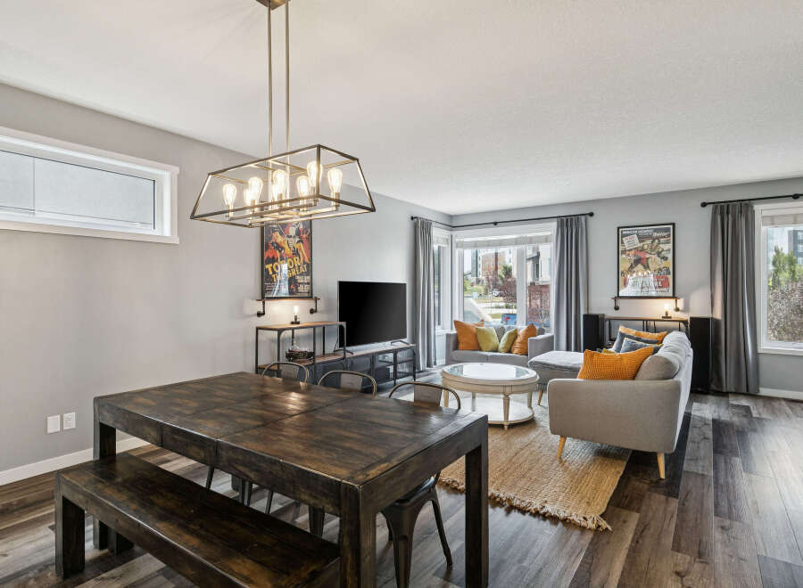 Experience modern living in this stylish open-concept space, featuring a spacious dining area with a rustic wooden table and bench, perfect for gatherings.