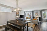 Experience modern living in this stylish open-concept space, featuring a spacious dining area with a rustic wooden table and bench, perfect for gatherings.