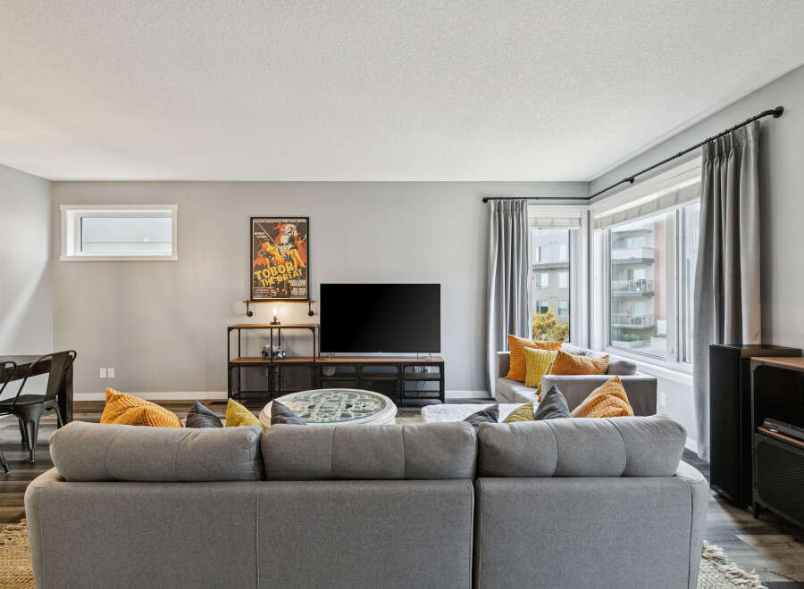 Step into this inviting living room, featuring a spacious sectional sofa perfect for gatherings and a large television for entertainment.