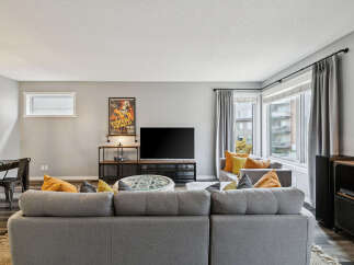 Step into this inviting living room, featuring a spacious sectional sofa perfect for gatherings and a large television for entertainment.