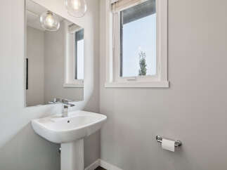 This modern bathroom features a sleek pedestal sink with a chrome faucet, complemented by a large vanity mirror and elegant pendant lighting.
