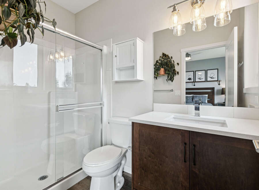 This modern bathroom features a sleek glass-enclosed shower and a stylish vanity with a dark wood cabinet and white countertop.