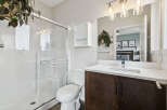 This modern bathroom features a sleek glass-enclosed shower and a stylish vanity with a dark wood cabinet and white countertop.