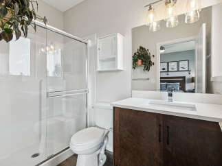 This modern bathroom features a sleek glass-enclosed shower and a stylish vanity with a dark wood cabinet and white countertop.