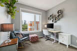 This home office features a comfortable rocking chair with a decorative pillow, a plush ottoman, and a stylish desk with a computer.