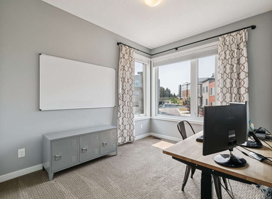 This home office features a large whiteboard for brainstorming and a grey locker-style cabinet for storage.