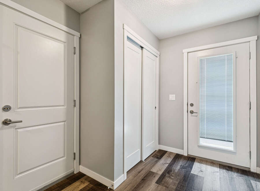 Step into this inviting entryway featuring a sleek white door with a modern brushed nickel handle, perfect for welcoming guests.