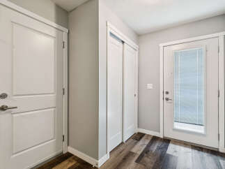 Step into this inviting entryway featuring a sleek white door with a modern brushed nickel handle, perfect for welcoming guests.
