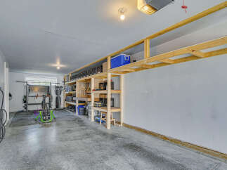 Maximize your storage and organization in this spacious garage featuring custom-built wooden shelving units.
