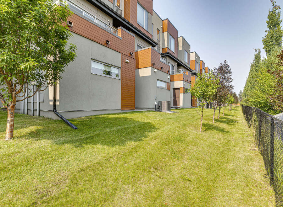 Discover modern living in this stunning townhouse complex, featuring a sleek design with warm wood accents and expansive windows.