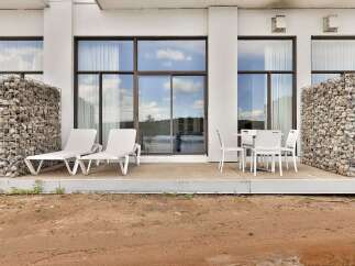 Enjoy the outdoors on this spacious patio featuring comfortable lounge chairs and a dining set, perfect for relaxation and al fresco meals.