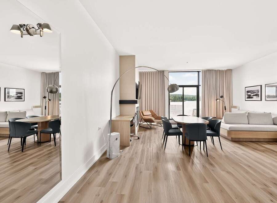 Experience modern living in this spacious open-concept condo, featuring a sleek dining area with upholstered chairs and a large oval table perfect for gatherings.
