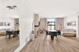 Experience modern living in this spacious open-concept condo, featuring a sleek dining area with upholstered chairs and a large oval table perfect for gatherings.