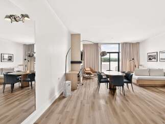 Experience modern living in this spacious open-concept condo, featuring a sleek dining area with upholstered chairs and a large oval table perfect for gatherings.