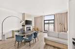 Experience modern living in this spacious suite featuring a sleek dining area with an oval table and comfortable chairs, perfect for intimate meals.