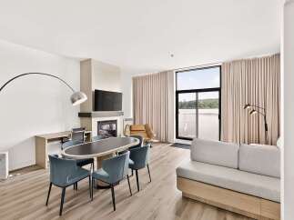 Experience modern living in this spacious suite featuring a sleek dining area with an oval table and comfortable chairs, perfect for intimate meals.