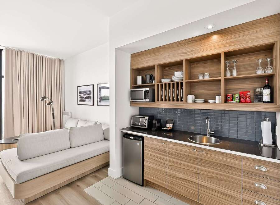 This modern studio apartment features a well-equipped kitchenette with ample storage, a microwave, and a mini-fridge, perfect for preparing meals.