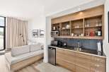 This modern studio apartment features a well-equipped kitchenette with ample storage, a microwave, and a mini-fridge, perfect for preparing meals.