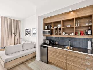 This modern studio apartment features a well-equipped kitchenette with ample storage, a microwave, and a mini-fridge, perfect for preparing meals.