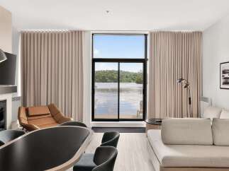 Experience breathtaking lake views from this stunning living space, featuring a modern fireplace and comfortable seating.