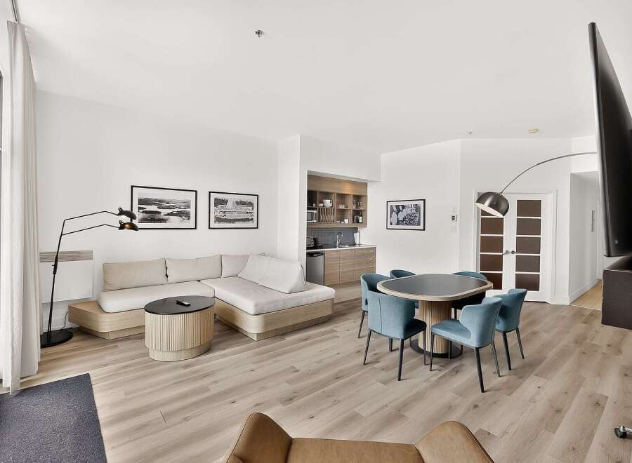 Experience modern living in this stylish open-concept suite, featuring a spacious sectional sofa and a sleek dining area perfect for entertaining.
